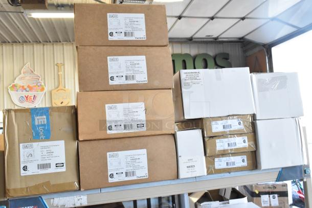 Stack of Dual Lite LED emergency light boxes, models EVHC, EVHCEZP, in new condition. Labels detail specs and quantity.