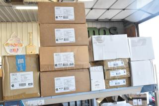 Stack of Dual Lite LED emergency light boxes, models EVHC, EVHCEZP, in new condition. Labels detail specs and quantity.