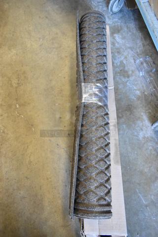 Rolled black floor mat with diamond pattern, wrapped in plastic. Set of 6 in new condition, ready for auction.