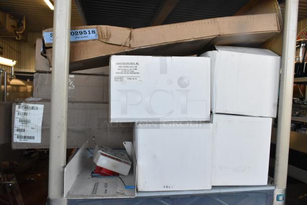 Boxes containing 6 various items, including an emergency light, stacked on a shelf. Labels show part numbers and manufacturer details.