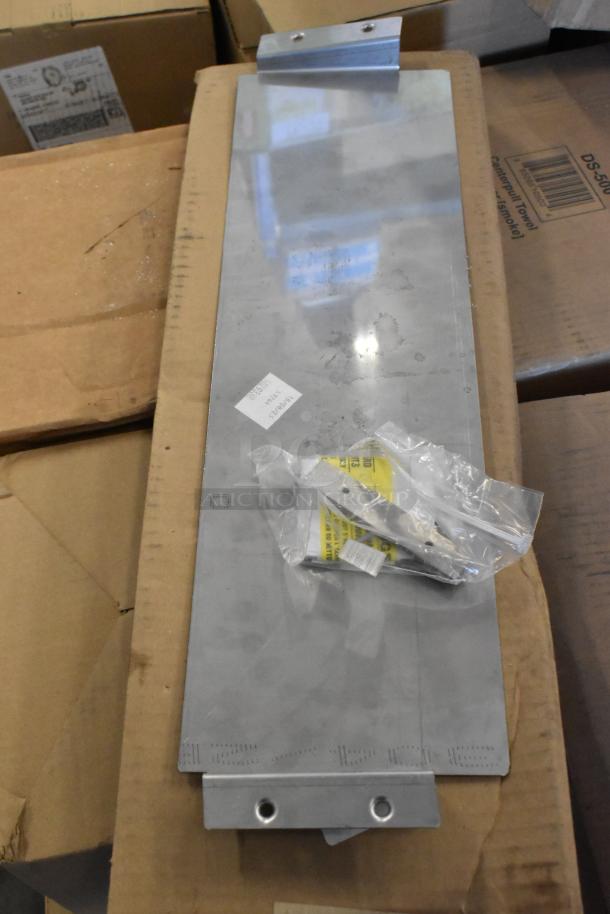 Six miscellaneous items, including a metal emergency light panel, resting on cardboard. Labels and packaging bags visible.