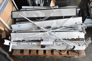 Eight white rectangular light fixtures on a pallet, various wires and components visible, used condition. Label states "QTY: 8."