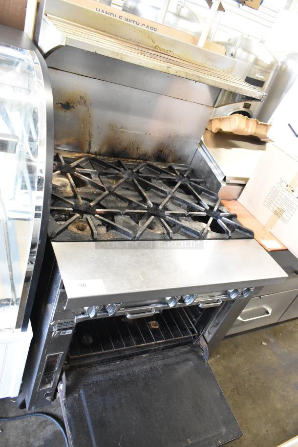 Southbend stainless steel 6 burner gas range with oven and backsplash, showing signs of use, includes function labels.