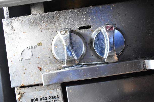 Southbend stainless steel commercial gas range controls, showing wear, with visible branding and manufacturer contact number.