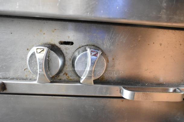 Southbend commercial gas range knob detail, shows moderate wear. Stainless steel with two burner control knobs visible.