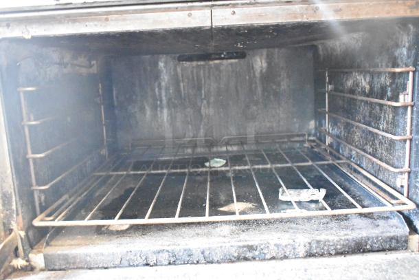 Southbend commercial oven interior with metal rack, showing signs of wear; part of a 6-burner gas range setup.