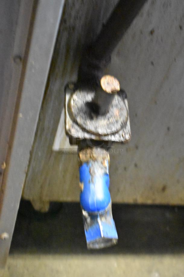 A close-up of a valve with a blue handle connected to a worn, rusted pipe, part of a Southbend commercial gas range.