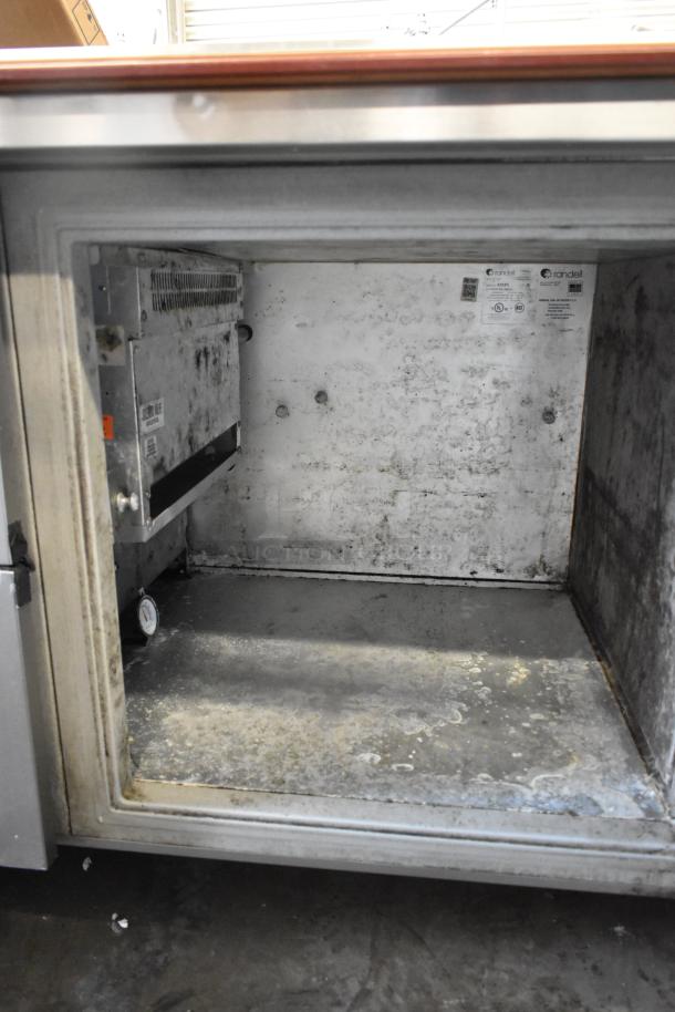 Delfield stainless steel commercial pizza prep table, 115V, 1 phase. Interior shows wear; visible labels include model and safety info.