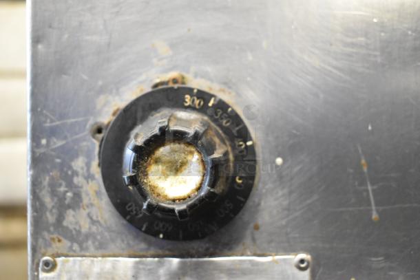 Close-up of temperature dial on Bakers Pride 4151 pizza oven. Numbers visible, showing signs of wear on stainless steel surface.