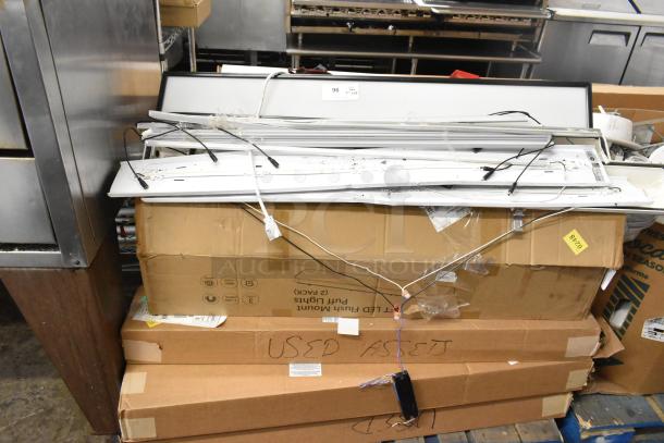 Boxes of various light fixtures, wires exposed, labeled as "USED ASSETS." Mixed condition, stacking displays quantity.