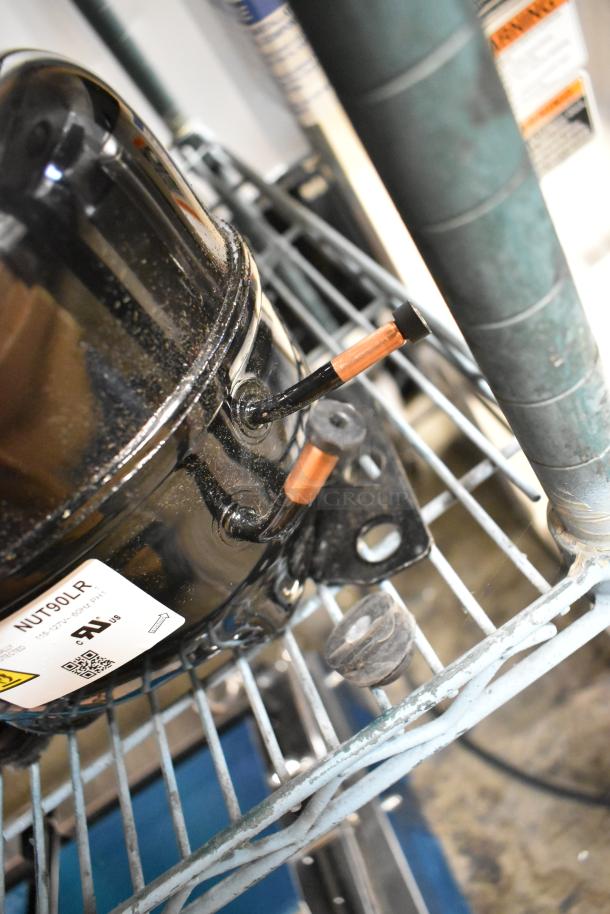 Brand new scratch and dent Cubigel NUT90LR compressor. 115-127 volts, 1 phase. Manufacturer label visible.