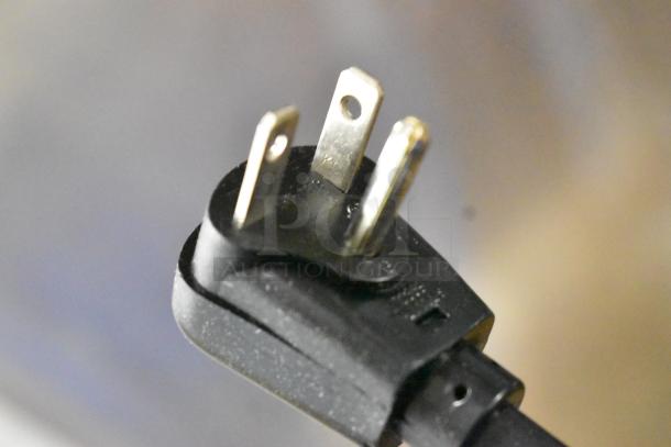 Close-up of a three-prong plug for the Amana HDC182 Stainless Steel Commercial Microwave, showing metal prongs and black plastic casing.