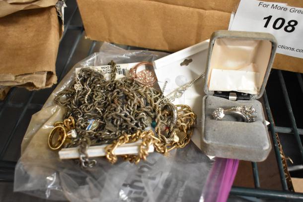 Lot of various jewelry including chains, rings, and a boxed ring. Mixed metals, varied conditions, includes a "Made in China" tag.