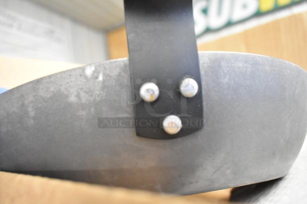 Close-up view of a metal skillet's riveted handle, showing signs of wear and patina, indicating its condition and durability.