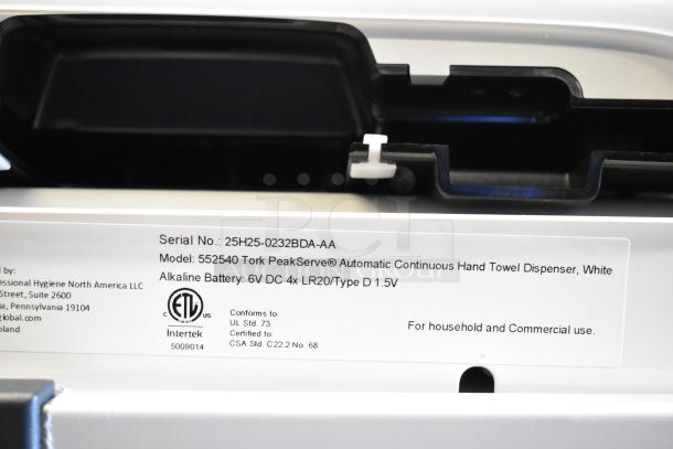 "Label on Tork PeakServe 552540 White Automatic Paper Towel Dispenser, detailing model and battery info."