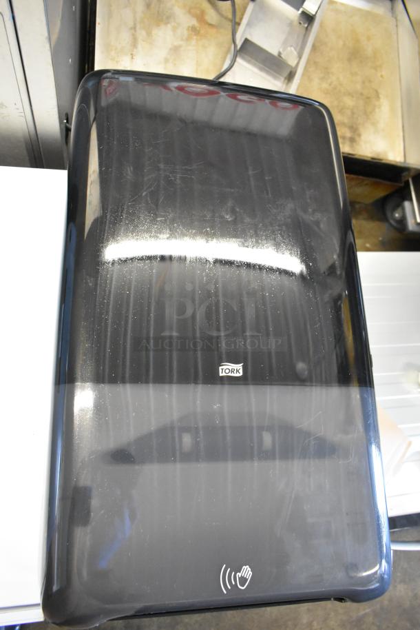 Tork PeakServe 552548 Black Automatic Paper Towel Dispenser, new, features scratch and dent marks, touchless operation symbol.