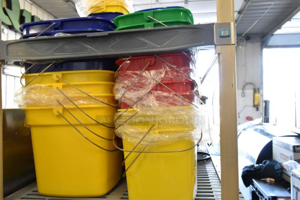 Lot of 58 Noble Poly Buckets in assorted colors stacked on a shelf. Brand new with minor scratches and dents.