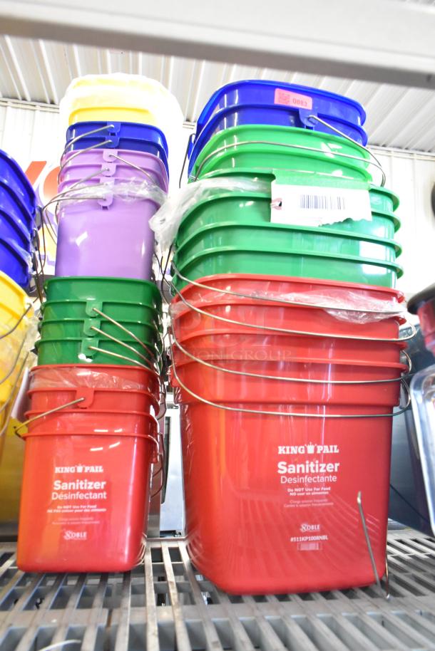 Lot of 58 Noble poly buckets, brand new with minor scratches and dents. Includes red, green, purple, yellow, and blue varieties. Marked as sanitizer buckets with metal handles and visible barcodes.