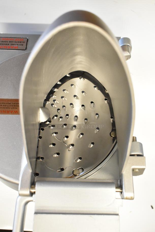 Brand new metal commercial pelican head with grating blade, slight scratches, durable steel construction, visible warning label.