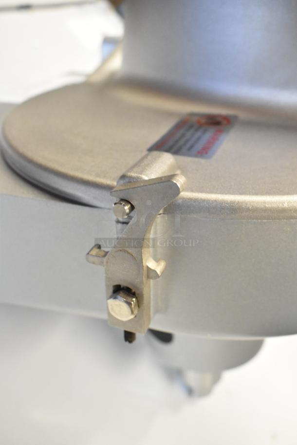 Brand new metal commercial pelican head with grating blade, showing minor scratches; features secure bolt and warning label.