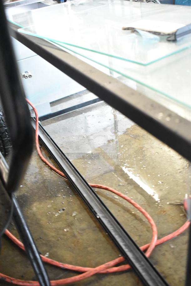 Glass display case with missing back and bottom panes. Visible metal frame with glass panels. Used condition.