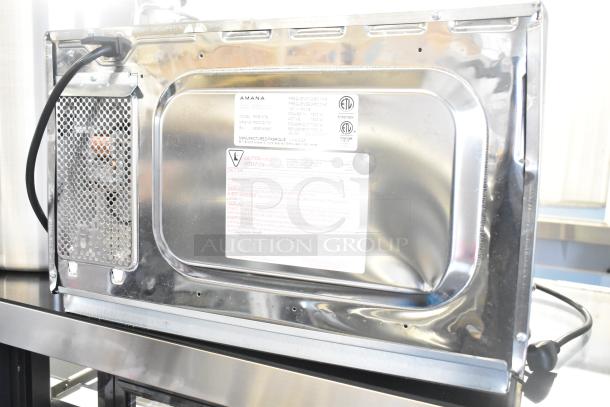 2025 Amana RCS10TS stainless steel commercial microwave, 120 volts, rear view with model label and power cord visible.