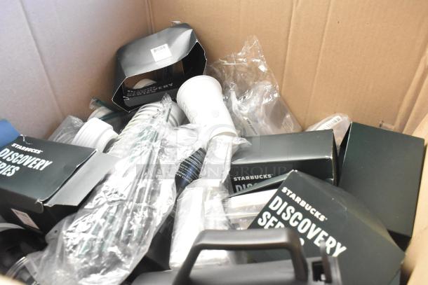 Lot of Starbucks items in a box, includes cups, straws, lids, some in original packaging. Mixed condition, labeled "Discovery Series."