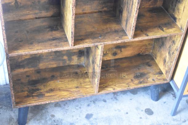 Wooden bookshelf with visible age marks, featuring multiple compartments, sturdy construction, and rustic finish.