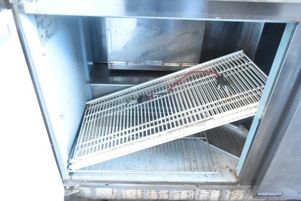 Delfield 4460N-24M-QZN stainless steel prep table interior, showing wire shelves and a power cord. 115V, 1 Phase.
