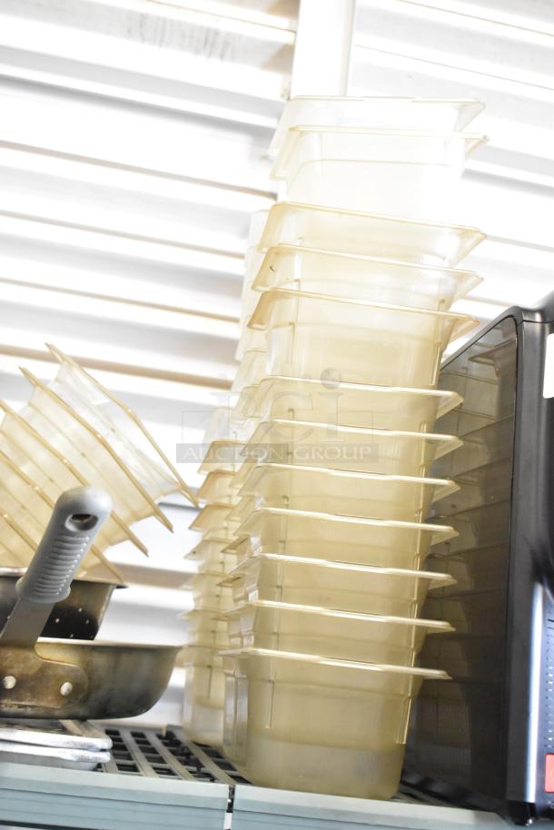 Lot of stainless steel and poly drop-in bins stacked on a shelf, used condition, ideal for kitchen or storage solutions.