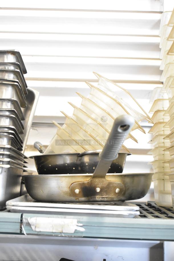 Lot of stainless steel and poly drop-in bins, stacked and used, suitable for restaurant or kitchen storage.