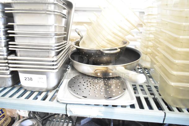 Lot of stainless steel and poly drop-in bins stacked on a shelf, includes pans and colander. Label indicates quantity "238."
