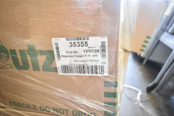 18 boxes of 14 oz Utz Pumpernickel Pretzel bags, marked "Best by 11/17/25," in sealed packaging.