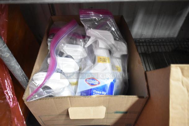 A box containing multiple bottles of Clorox Clean-Up Disinfectant Spray, stored in clear zipper bags.