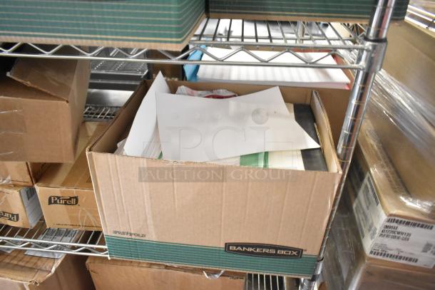 Cardboard box on metal shelf containing mixed office supplies including folders and paper sheets. Box labeled Bankers Box.