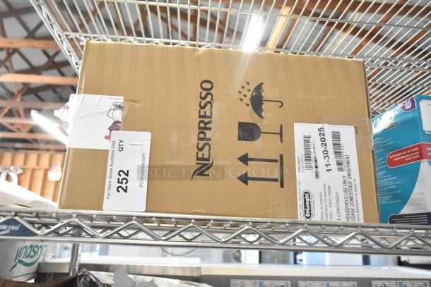 DeLonghi ENV150GY Nespresso VertuoPlus coffee machine in sealed box on shelf. Visible product labels with 11-30-2025 date.