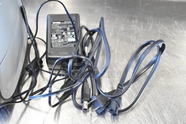 Dymo LabelWriter 450 Twin Turbo label printer with power adapter and cables on a metal surface.