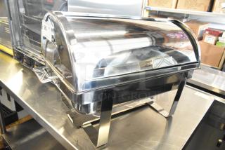 Brand new stainless steel chafing dish with minor scratches. Includes a roll-top lid and sturdy legs. Suitable for catering.