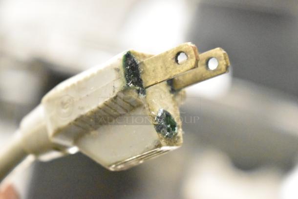Close-up of a worn plug for model 7510 Stainless Steel Meat Slicer. Visible corrosion and dirt on metal prongs.