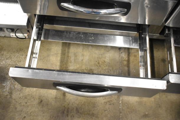 Stainless steel commercial 4-drawer chef base on casters, 115 volts, 1 phase, polished finish, open drawer view.