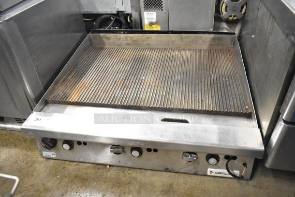 Garland stainless steel commercial gas-powered ridged griddle, used condition, with control knobs and Garland logo visible.