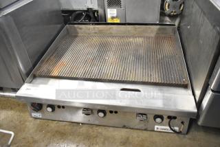 Garland stainless steel commercial gas-powered ridged griddle, used condition, with control knobs and Garland logo visible.