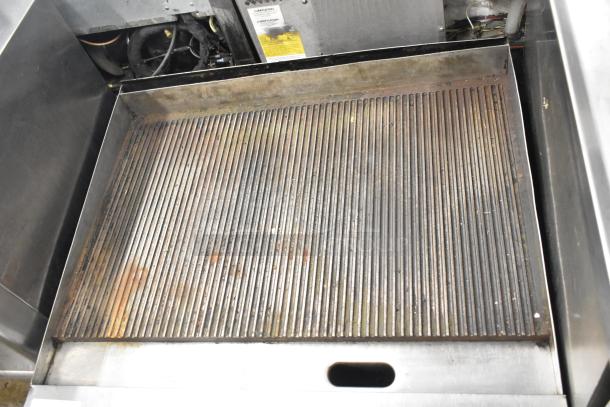 Garland stainless steel commercial gas-powered ridged griddle, countertop model, showing surface wear and grease stains.