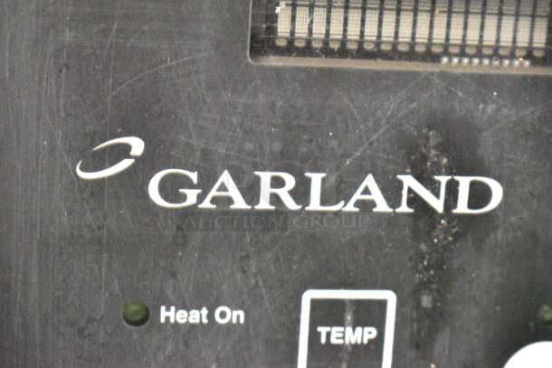 Garland stainless steel commercial electric convection oven, half size, solid door, metal racks, on casters, logo displayed.