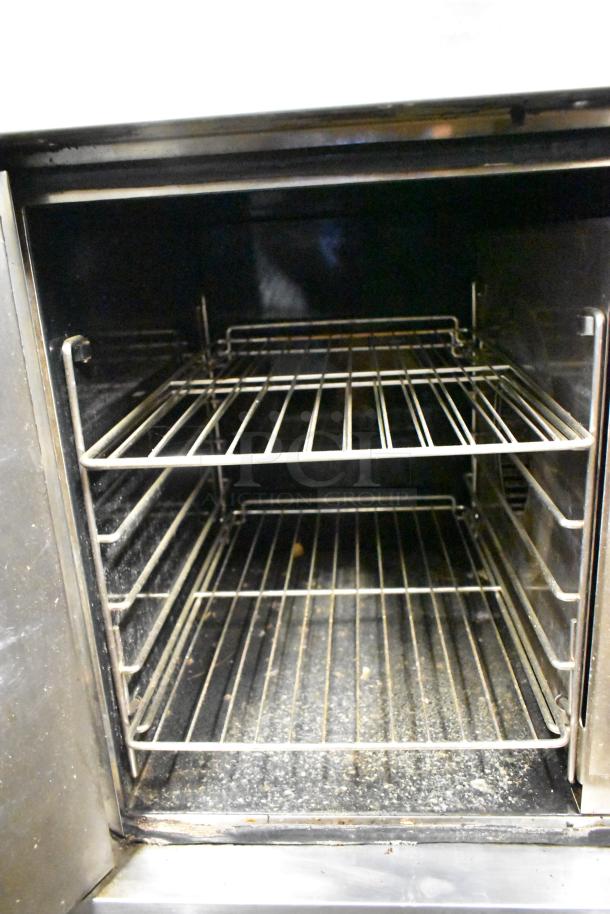 Garland stainless steel commercial convection oven with solid door, metal racks, on casters; interior shows use.