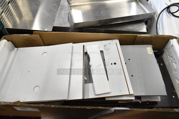 Cardboard box containing white and gray flat-pack boards, possibly furniture or shelving components, in new condition.