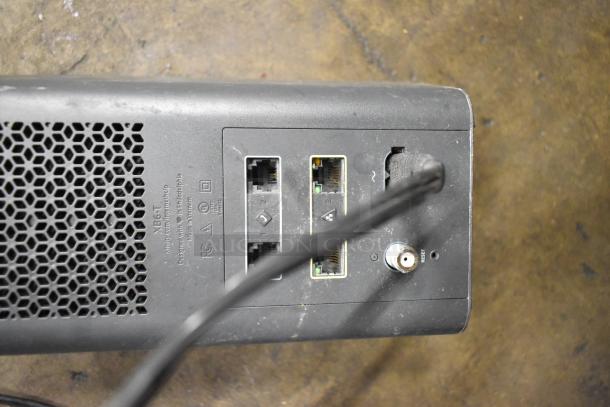 Back view of Xfinity router with Ethernet and coaxial ports, moderate wear, visible model markings and FCC certification label.