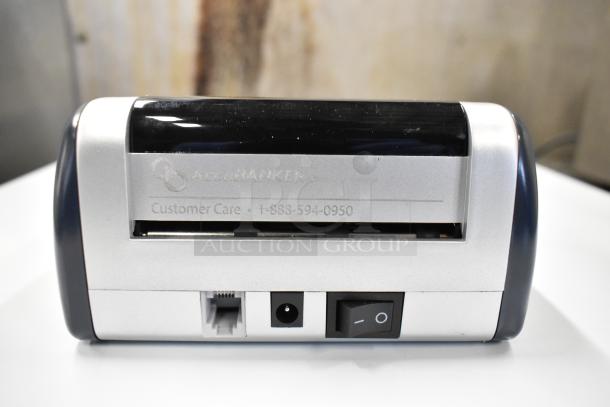AccuBanker D450 Counterfeit Bill Detector, silver with on/off switch, customer care info visible. Part of a 2-item auction set.