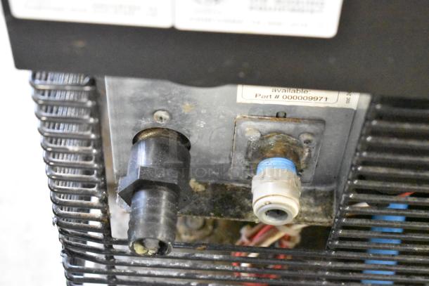 Manitowoc RNS0244A ice machine connections close-up showing part number 000009971 label. Stainless steel exterior.