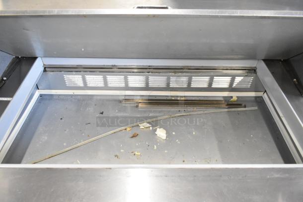 Beverage Air SPE48-18M-HMP stainless steel prep table interior, showing space for organizing ingredients. Visible wear and crumbs present.